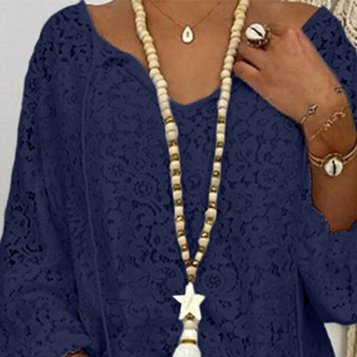 Woman wearing blue lace top with beaded necklace and accessories.