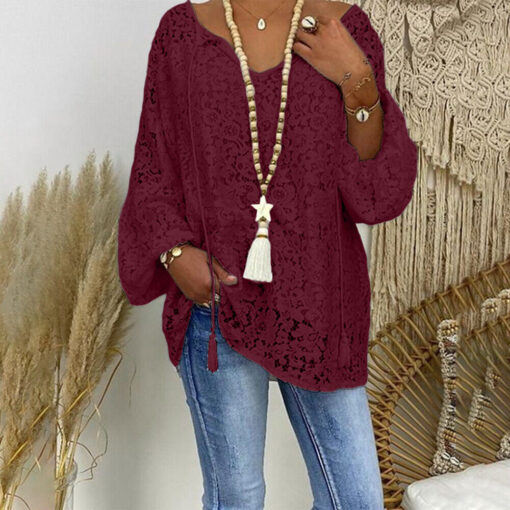 Woman in burgundy lace blouse and jeans with accessories.