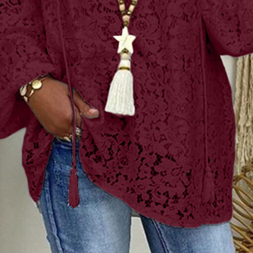 Woman in lace burgundy blouse and jeans.