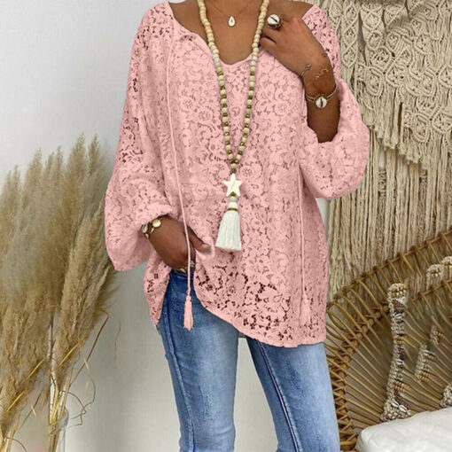 Woman in pink lace blouse and jeans with accessories.