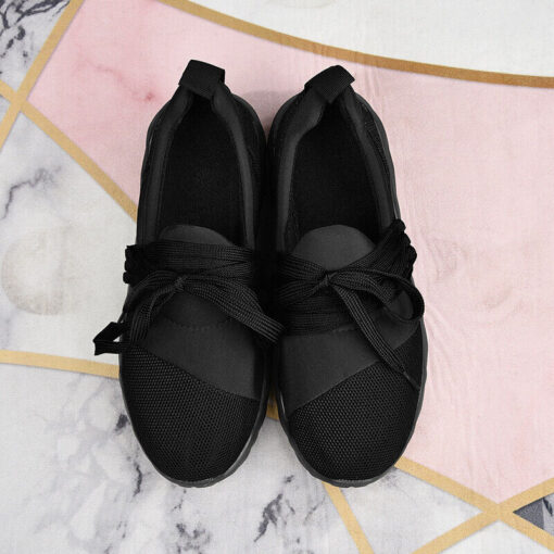 Black ballet flats with bow on patterned background.