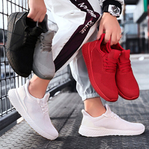 Person holding red sneaker, other foot in white shoe.