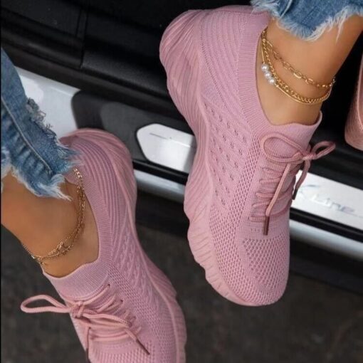 Pink sneakers and ankle bracelet on woman stepping out of car.