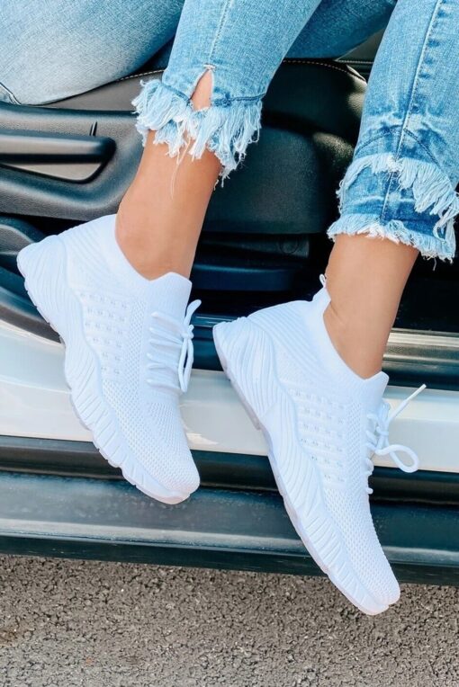 White sneakers and ripped jeans on person exiting car.