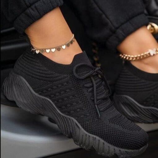 Black sneakers with heart ankle bracelet.