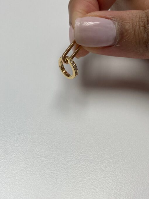 Gold diamond earring held by fingers.